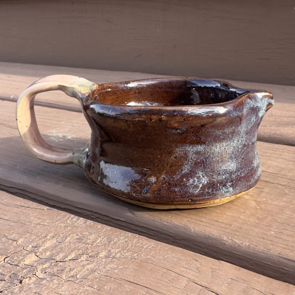 Finished creamer. Brown body with pinkish handle.